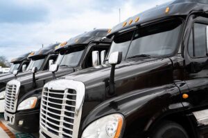 Fleet of black 18 wheeler commercial semi trucks