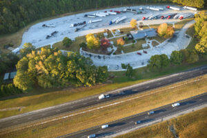 Top view of large rest area near busy multilane american freeway with fast moving cars and trucks. Recreational resting place during interstate traveling