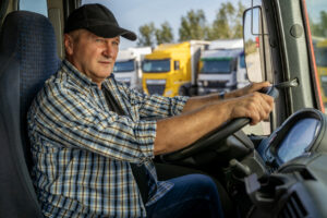 Closeup shot, amazing lighting, trucker sitting in front of wheel ready to start his day, parked trucks in the back