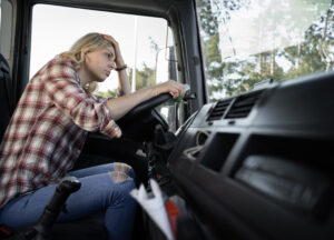 Depressed woman truck driver, sitting behind the wheel with no will to drive further. long line at customs