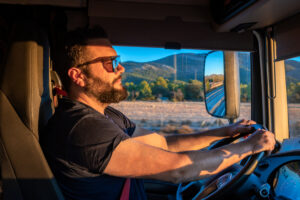 Heavy truck driver happy to be able to drive a truck, and making the gesture of OK, with the thumb up.