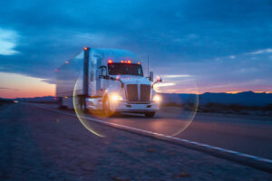 A white semi truck rumbled through the vast expanse of the Nevada Desert, with the majestic mountains in the background. The setting sun cast a golden glow, painting the scene with a serene beauty.