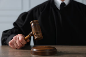 Judge with gavel sitting at wooden table, closeup