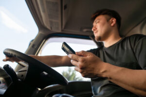 Truck driver driving while operating a smartphone