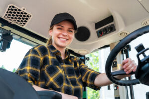 Portrait of woman tractor driver smiles while sits in cabin.