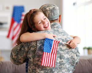 Happy girl daughter with american flag hugging father came back from US army