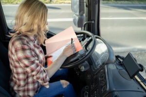 Woman truck driver filling up paper work , on steering wheel