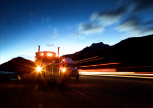 Illuminated Headlights Of Semi Truck Against Sky At Dusk