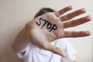 Teen boy protects himself with his hand in the palm of his inscription "stop"