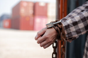 woman's hand trapped in an illegally smuggled container locked with chain and key. Efforts to escape from the confinement were tortured : Human Trafficking and Illegal Immigration.