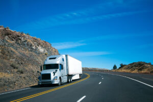 Modern semi truck and trailer on turning rocky windy road