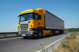 The truck carries cargo on the highway in the tilt van. Front view. Wide angle