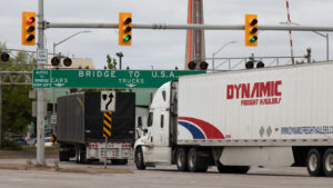 Transport Trucks Drive Under a "Bridge to USA" Sign in Windsor Ontario