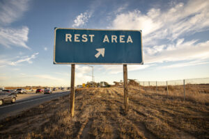 Blue Rest Area road sign with an arrow against a blue sky with clouds