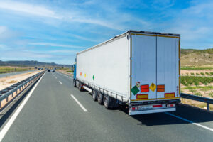 Large tonnage truck traveling on a highway with license plates and labels for dangerous goods, non flammable gases under pressure and oxidizing material. Category 5.1 in ADR.