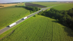 Aerial Top View of White Truck with Cargo Semi Trailer Moving on Road in Direction f Loading Warehouse Area.