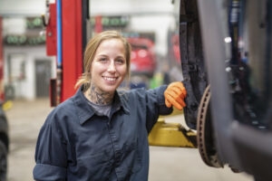 Handsome mechanic job woman in uniform working on car