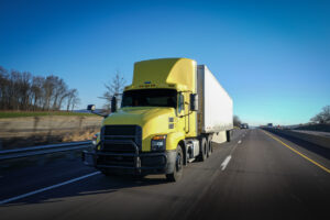 Big yellow 18 wheeler truck delivering on highway road