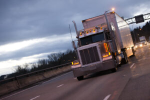 Classic american big rig semi truck tractor and reefer trailer on evening twilight highway road